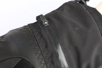 Close-up of a black textile product with a black zipper, stitched seam, and small metal slider, shown against a white background.
