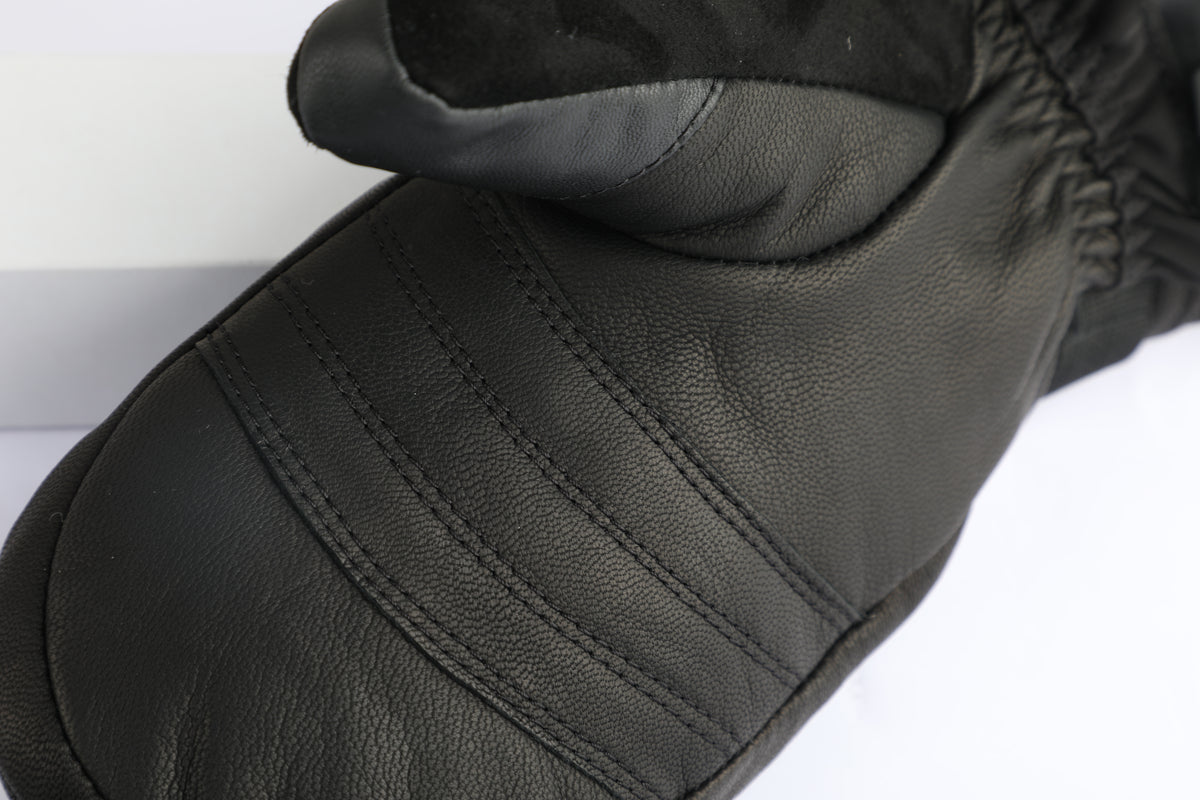 A close-up of a black leather mitten with stitched paneling and a dark gray fabric cuff, shown on a white background.